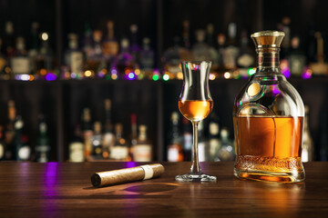 close up view of cigar, bottle of rum and a glass aside on color back. 