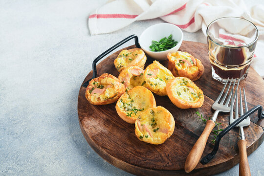 Delicious egg muffins with green onions, bacon, cheese and tomatoes on wooden board on light background. Healthy high protein and low carb breakfast. Homemade food.