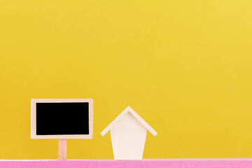 House model and blackboard with announce and offer for sale put on the pink foam on bright yellow color background in the office, Loan for business investment sell the real estate or buy home concept.