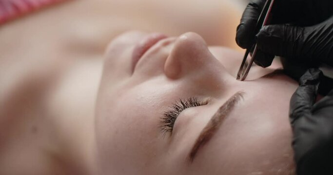 Beauty procedure: cosmetologist does eyebrow plucking, eyebrow correction in the beauty salon, 4k Prores