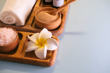 Top view spa set  oils, sea salt and clay scrub on a wooden tray. Self-care concept.Blue background. Copy space.