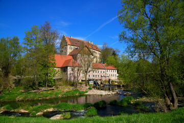 Das Museumsschloss Aschach in der Bayerischen Rhön bei herrlichen Frühlingswetter, idyllisch gelegen in der Landschaft mit einem Fluss