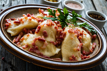 Dumplings - cheese noodles with onion and bacon on wooden background
