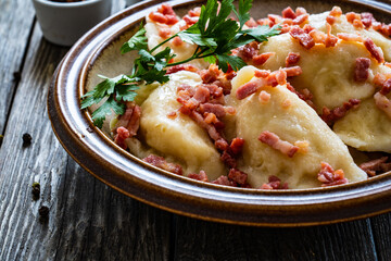 Dumplings - cheese noodles with onion and bacon on wooden background
