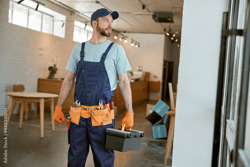 Wall mural male worker holding plastic box with tools