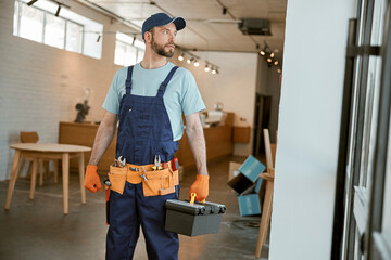 Male worker holding plastic box with tools