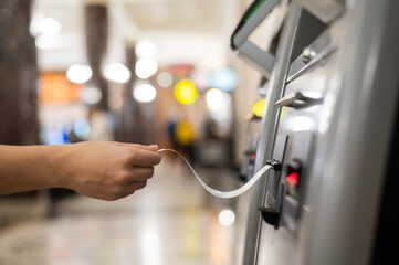A woman takes a train ticket from a self-service ticket office.