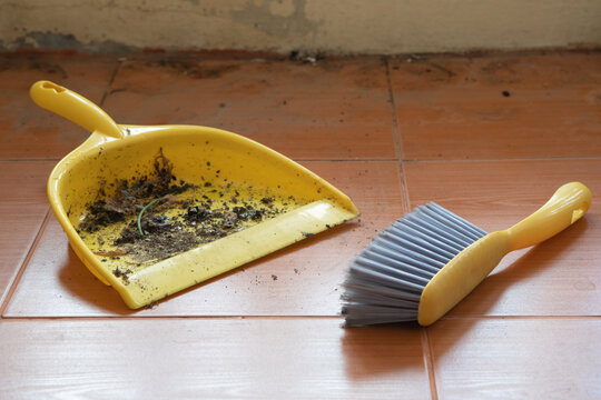 The yellow dustpan and brush are being used. with dust and dirt inside