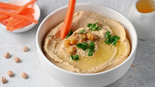 Eating hummus with carrot. hummus with sesame and olive oil. Healthy vegan food. Vegetarian dish. Mezze chickpeas. Kosher food.