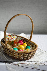 Fototapeta na wymiar Easter card. Willow branches, a basket with painted eggs and festive Easter cakes.