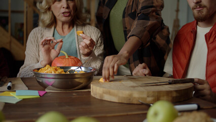 Young woman takes a slice of pumpkin from the dinner table and tastes