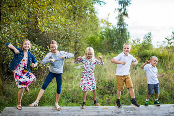 Five cute kids dancing outdoors on log