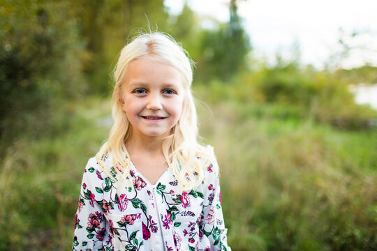 Stunning young blonde girl wearing flower dress outside.