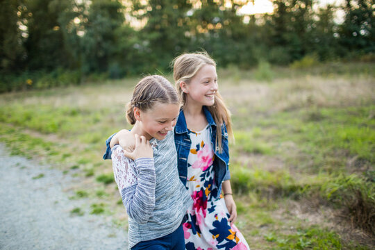 Two joyful girls laugh, smile, play outside.