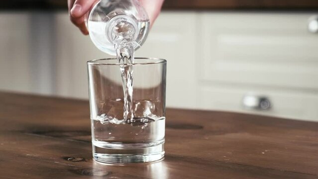 Male hand pouring clean water into a glass, close-up