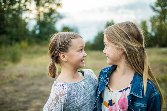Two girls playfully making funny faces at each other outside.