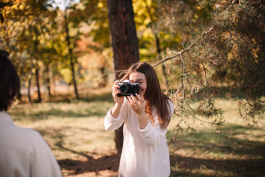 Happy young woman photographing girlfriend in park