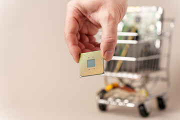 Trolley from supermarket filled with computer components. Male hand holding cpu. Selective focus.