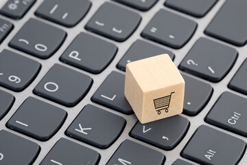 Wooden block with shopping cart graphic on computer keyboard