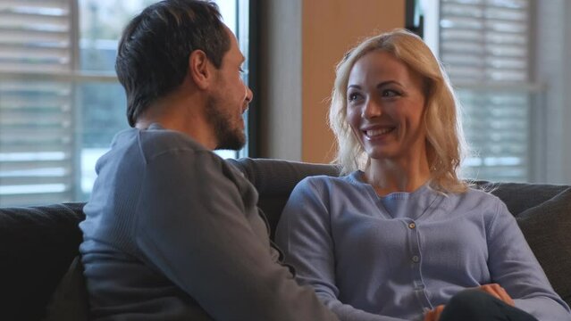 The beautiful couple sitting on a couch and talking. slow motion