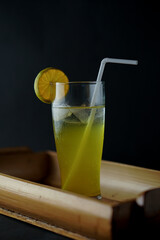 a refreshing drink called orange squash, served on a bamboo tray, on a black background