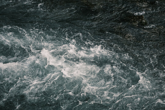 Seething stream of water in a mountain river. Top view, only water mass, splashes, foam, turbulent flow. Theme of the power of water. Concept of water element. Dangerous rafting. © Olivia Rich