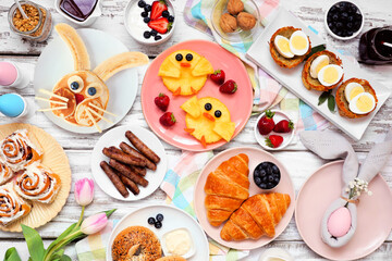 Easter breakfast or brunch table scene. Top view on a white wood background. Bunny pancake, egg...