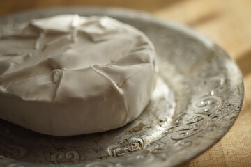 Whole round camembert cheese on a silver plate, side view