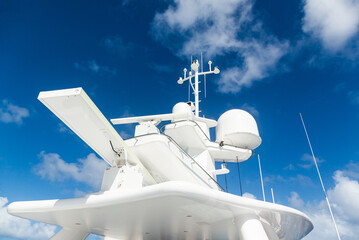 Fototapeta premium The mast of a large yacht with navigation equipment bottom view. Radar, signal lights, satellite dishes and equipment.