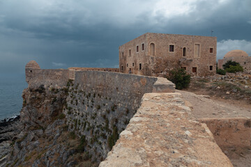 Stone wall, small tower and buildings of the ancient Venetian fortress Fortezza, Rethymno, Greece