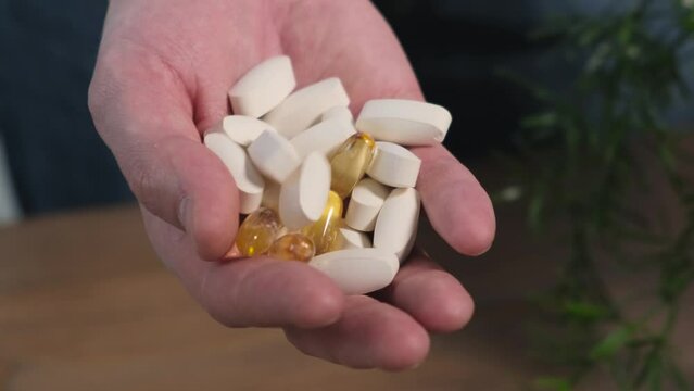 Man demonstrating amino acids and fatty acids omega 3 in his hand, close up. Concept: sports supplements, nutrition, bodybuilding, fitness