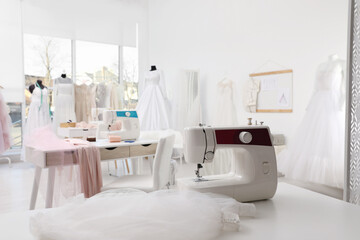 Obraz na płótnie Canvas Sewing machine and fabric on table in dressmaking workshop
