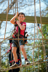 young boy navigating treetop ropes course