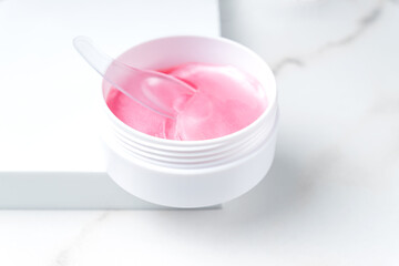 Hydrogel patches eye mask in pink colors on white podium The concept of cosmetology, facial skin care.