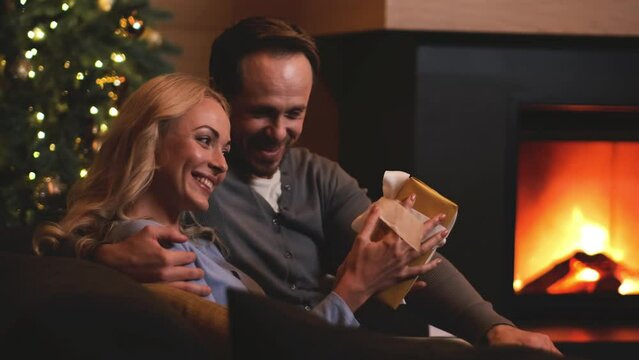 The man giving presents to his woman near the fireplace. slow motion