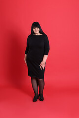 Beautiful overweight woman in black dress on red background