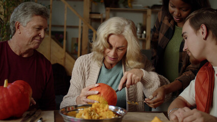  Grandmother tries to carefully cut off the top of the pumpkin and communicates with her grandson and husband