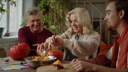  Grandmother tries to carefully cut off the top of the pumpkin and communicates with her grandson and husband