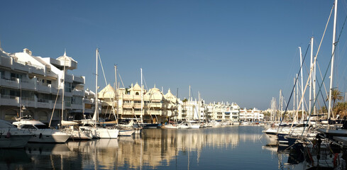 Boats in a yacht club in the Mediterranean sea, Malaga, Spain. Yachts moored in the port on sunny day, Reflection in water.