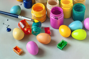 Easter eggs, acrylic paints and brushes on grey background, selective focus.