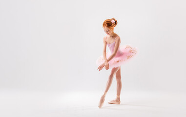 Little ballerina dancer in a pink tutu academy student posing on a white background