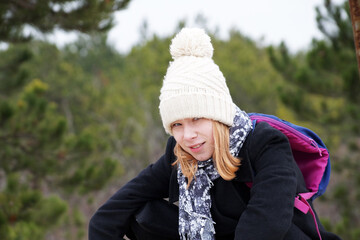 portrait of a teenage girl in a white hat with a pompom on the background of the forest