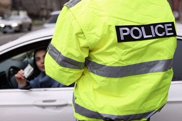 Woman giving bribe to police officer out of car window, closeup