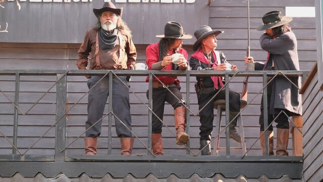 Group of senior man with cowboy costume stay in balcony and look down to other they also talk together about gun sometimes.