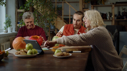 A family is watching videos how to carve pumpkins for Halloween