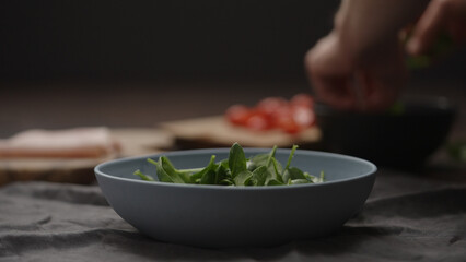 man making salad, put spinach leaves in blue bowl