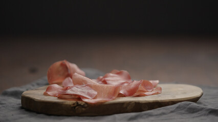 bresaola slices on olive cutting board