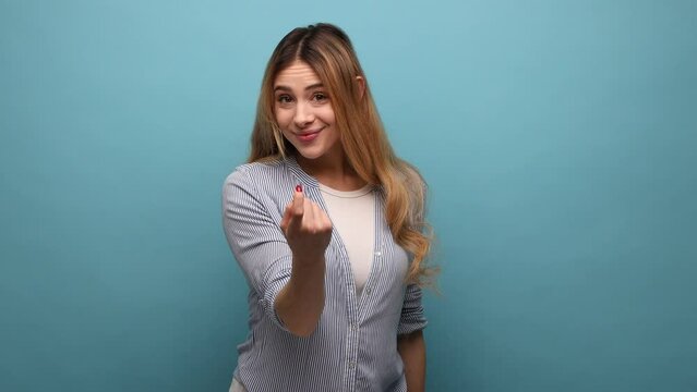 Come here. Portrait of attractive woman making beckoning gesture, inviting to come, flirting and looking playful, wearing striped shirt. Indoor studio shot isolated on blue background.