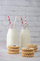 Homemade jam cookies and jar of milk on a marble table with subway tile white background.