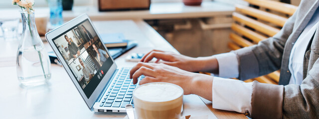 Group video call using laptop and camera. Woman sitting in cafe and has remote team conference